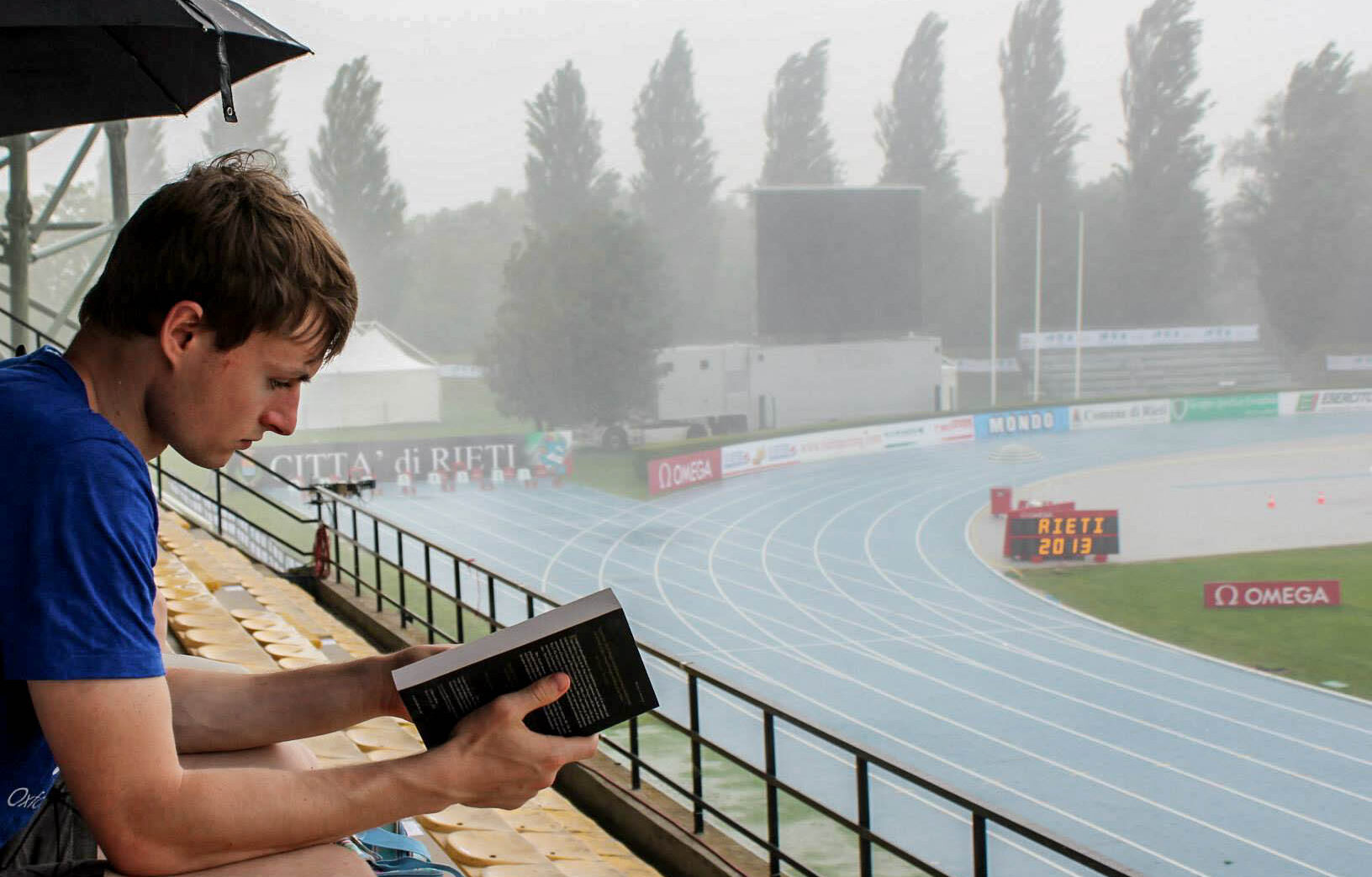 me reading a book in a stadium in the rain